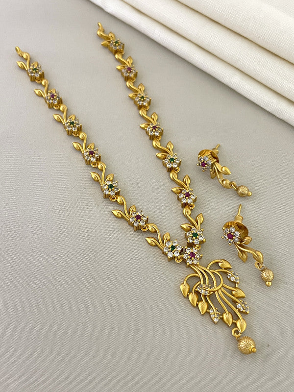 Gold necklace and earrings set with floral design and embedded gemstones.