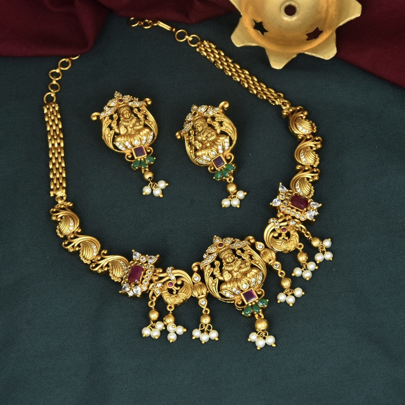 Gold necklace and earrings set with intricate designs and pearl accents.