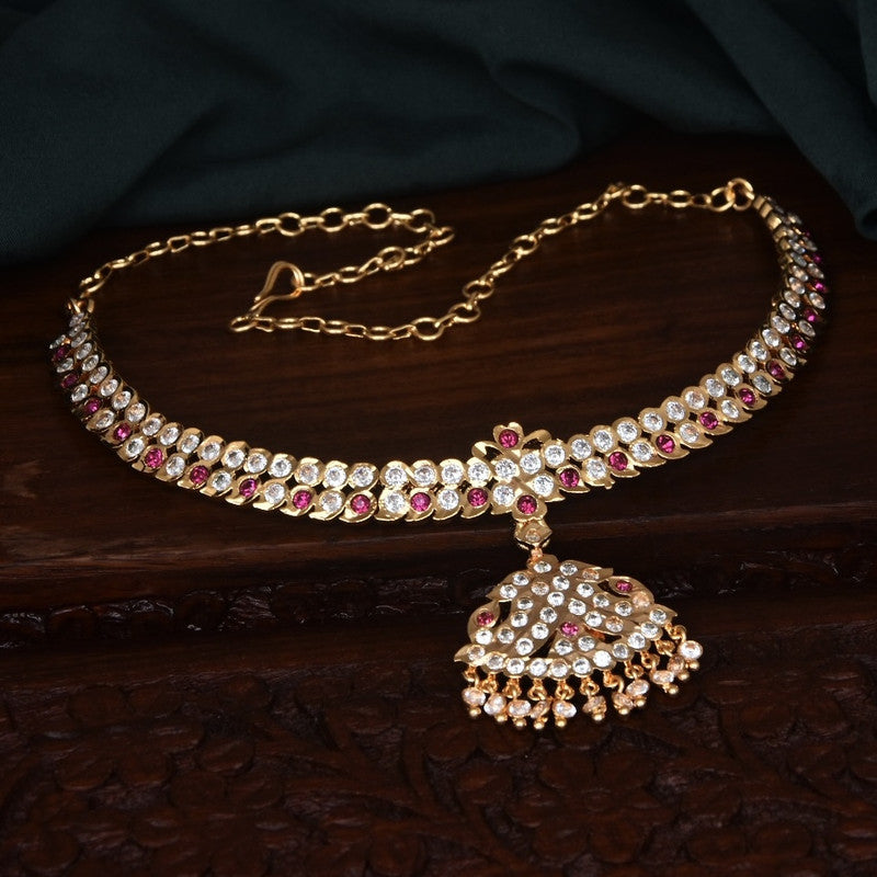 A gold choker necklace adorned with white and red gemstones, featuring a central pendant with intricate detailing and hanging beads.