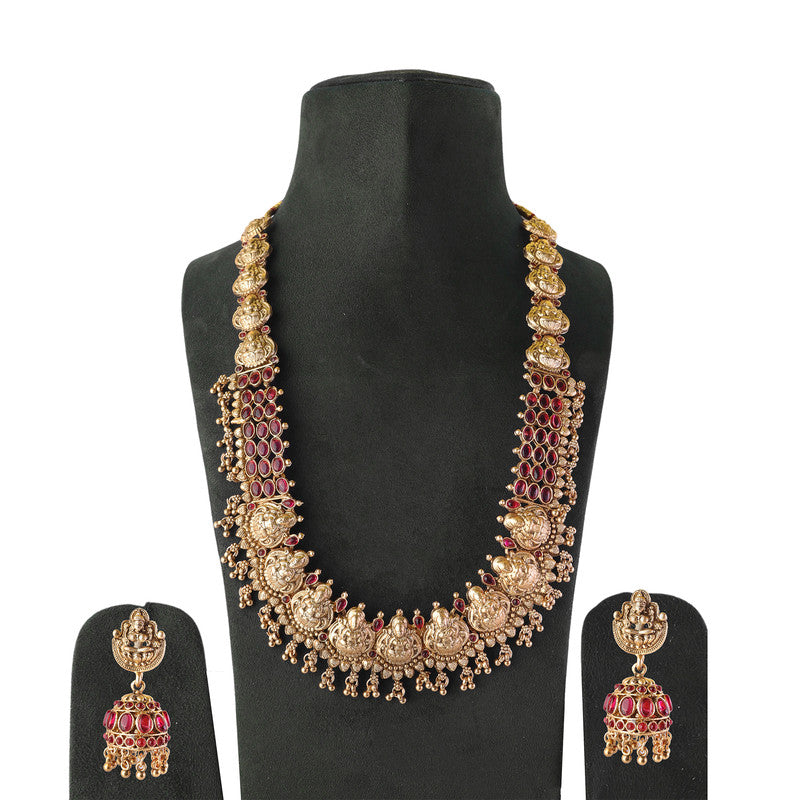 Gold necklace with intricate designs and red accents, accompanied by matching earrings, displayed on a black stand.