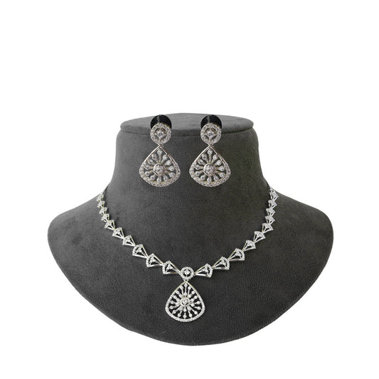 A silver necklace and matching earrings set displayed on a black jewelry bust. The necklace features a series of triangular links with a central teardrop pendant, and the earrings are teardrop-shaped with intricate detailing.