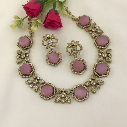 A jewelry set featuring a necklace and matching earrings with pink hexagonal stones and clear crystals.