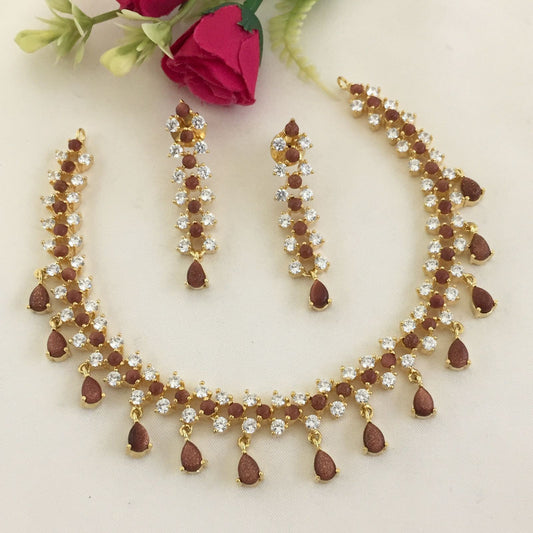 Gold necklace and earrings set with red and white gemstones.