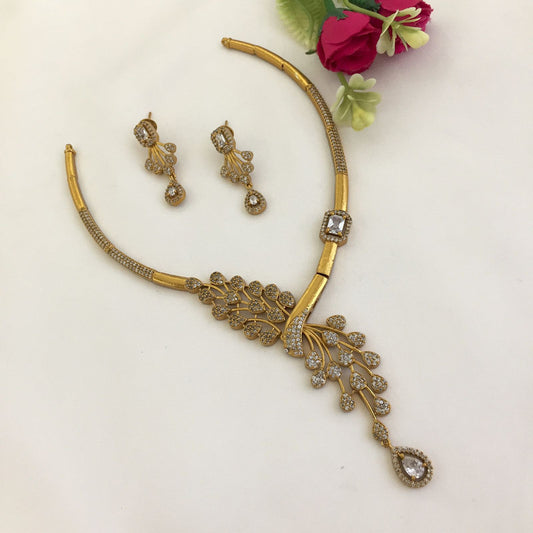 Gold necklace and matching earrings set with intricate design and embedded stones.