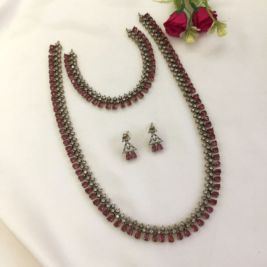 A jewelry set consisting of a necklace, a bracelet, and a pair of earrings, all adorned with red and white stones.