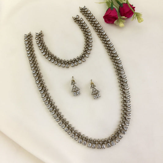 A set of silver jewelry including a necklace, a bracelet, a pair of earrings, and a smaller necklace, all adorned with teardrop-shaped crystals.