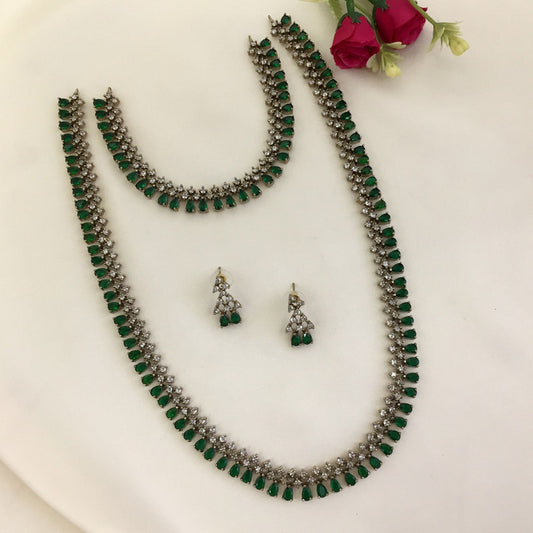 A set of jewelry consisting of a necklace, a choker, and a pair of earrings. The pieces feature green and white stones arranged in a symmetrical pattern.