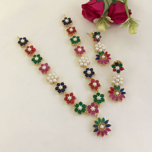 A set of colorful floral jewelry consisting of a necklace, a pair of earrings, and a pendant. The pieces feature flowers in red, green, blue, and pink with pearl accents.