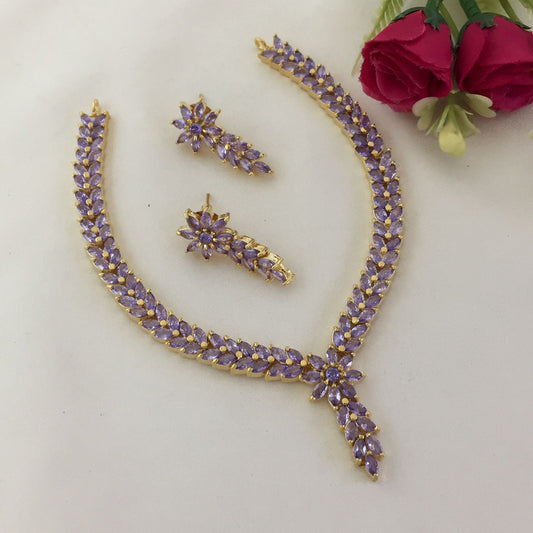 A gold necklace and matching earrings set adorned with purple gemstones.