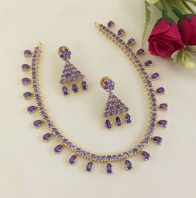 A gold necklace and matching earrings set adorned with purple gemstones.