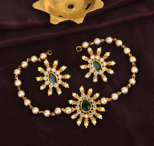 A gold-toned jewelry set featuring a bracelet and matching earrings. The pieces are adorned with pearls, green gemstones, and clear crystals arranged in a floral design.