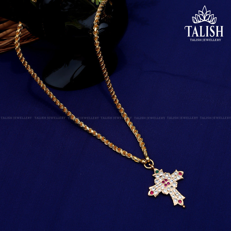 A gold chain with a cross-shaped pendant adorned with red and white gemstones, displayed on a dark blue surface.