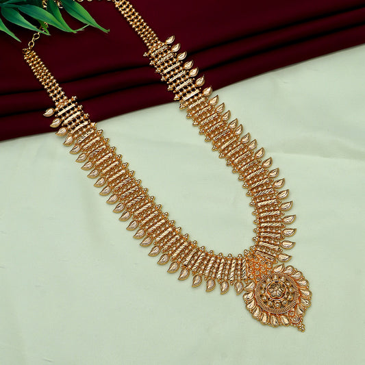 A gold necklace with intricate designs and a large circular pendant, displayed on a light green and maroon fabric background.