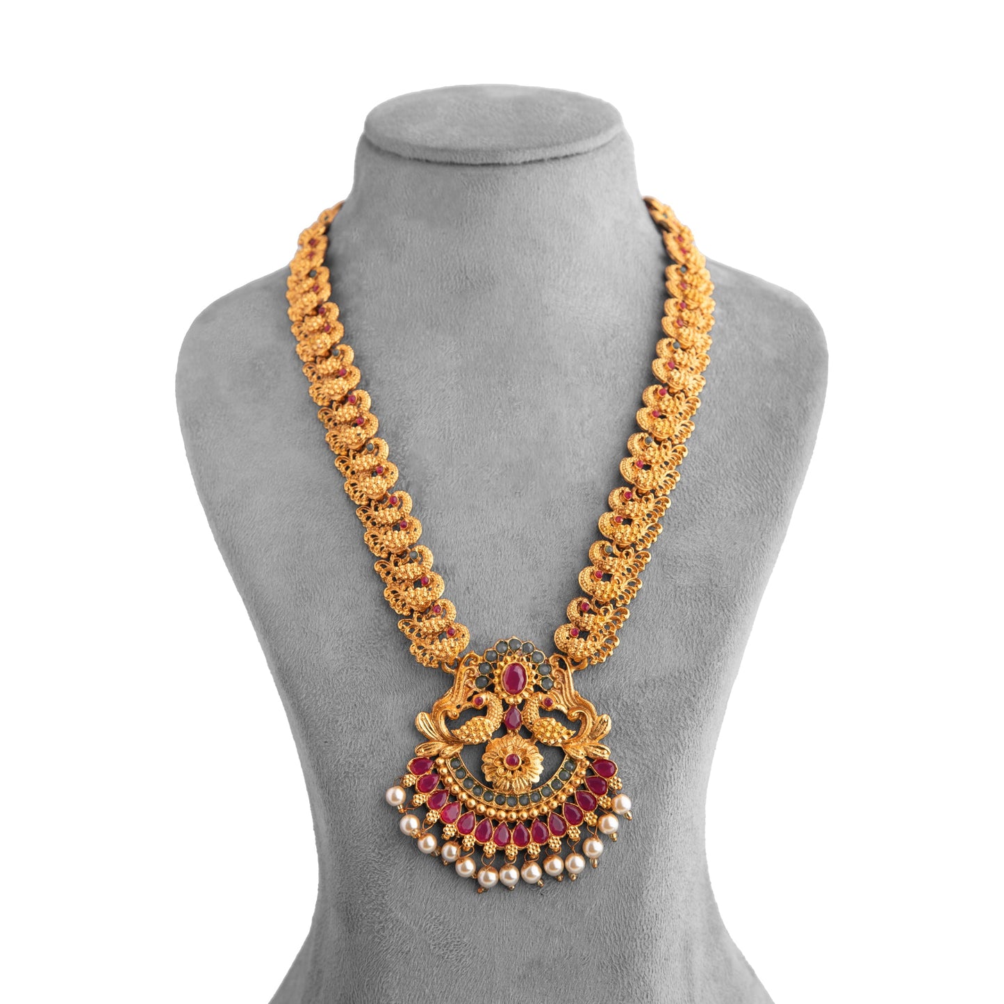 Gold necklace with intricate design and red gemstone accents displayed on a grey mannequin bust.