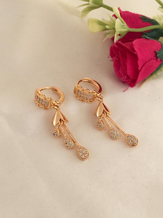 Gold earrings with dangling teardrop-shaped pendants encrusted with small diamonds.