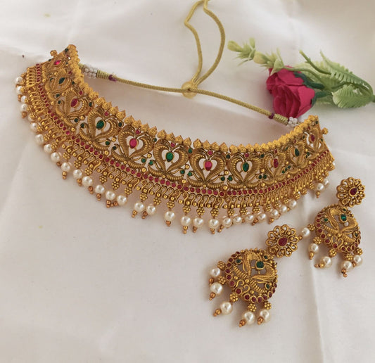 Gold choker necklace with intricate designs, adorned with pearls and colorful gemstones, accompanied by matching earrings.