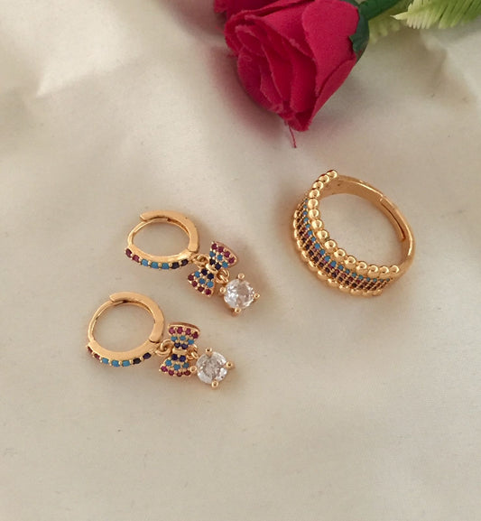 Gold hoop earrings with colorful gemstones and bow-shaped pendants, paired with a gold ring featuring a row of small gemstones.