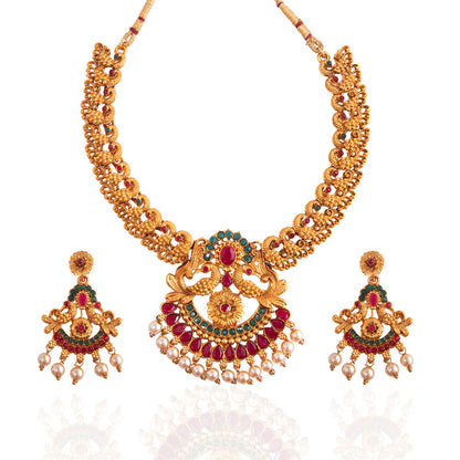 A traditional gold necklace set with intricate designs, featuring red and green gemstones, and matching earrings adorned with pearl drops.