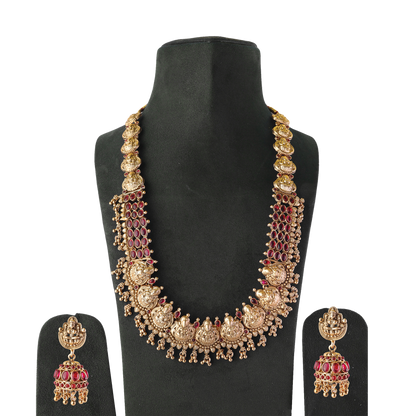 Gold necklace with intricate designs and matching earrings displayed on a black stand.