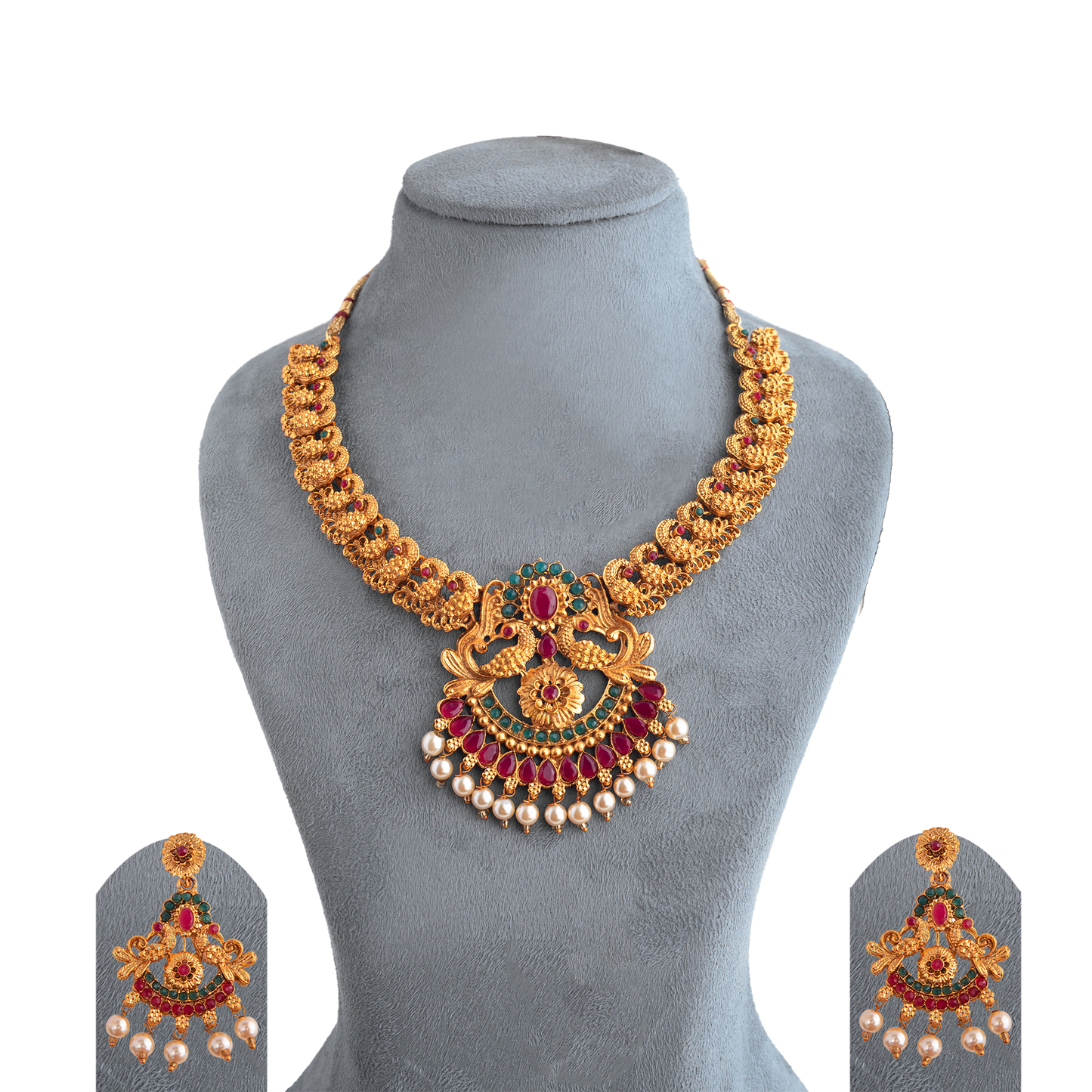 Gold necklace with intricate design, featuring red and green gemstones and pearl accents, displayed on a gray stand.