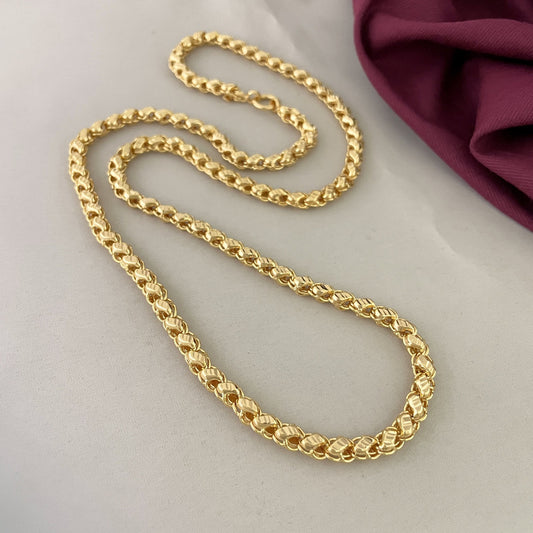 Gold chain necklace on a light surface.