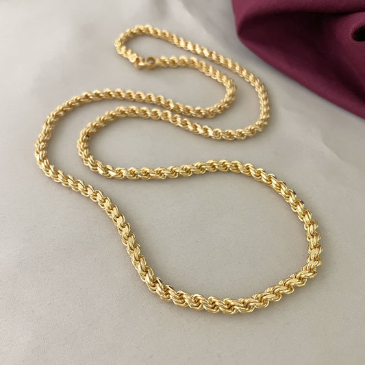 A gold rope chain necklace displayed on a light surface.
