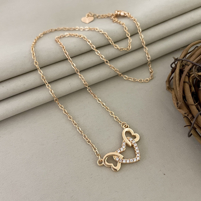 Gold necklace with two interlocking heart pendants, one adorned with small crystals.
