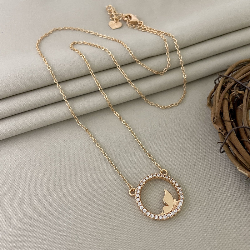 A gold necklace with a circular pendant featuring a butterfly design in the center, surrounded by small gemstones.