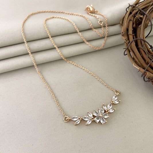 Gold necklace with a floral design featuring clear gemstones.