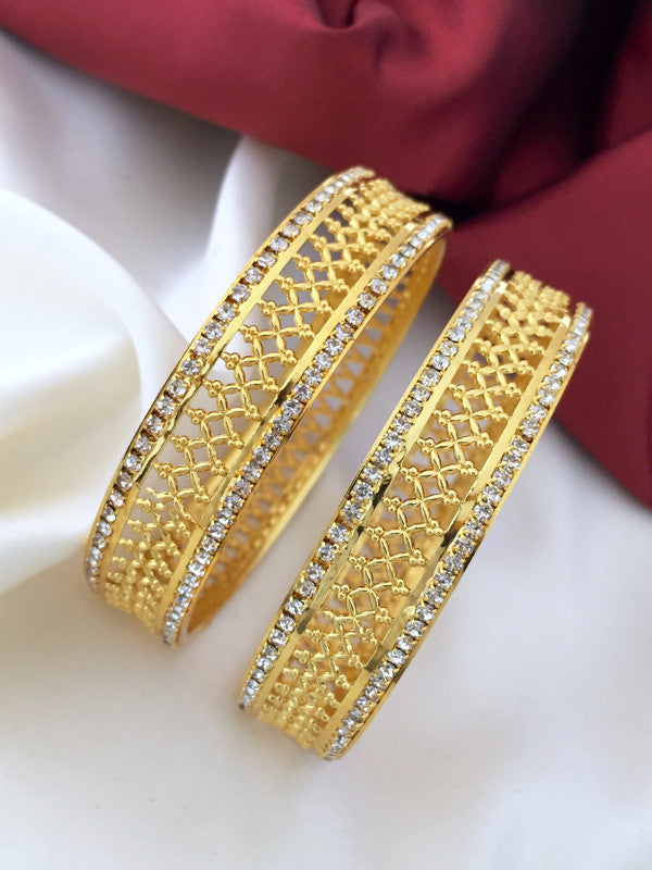 Two intricately designed gold bangles with diamond accents.