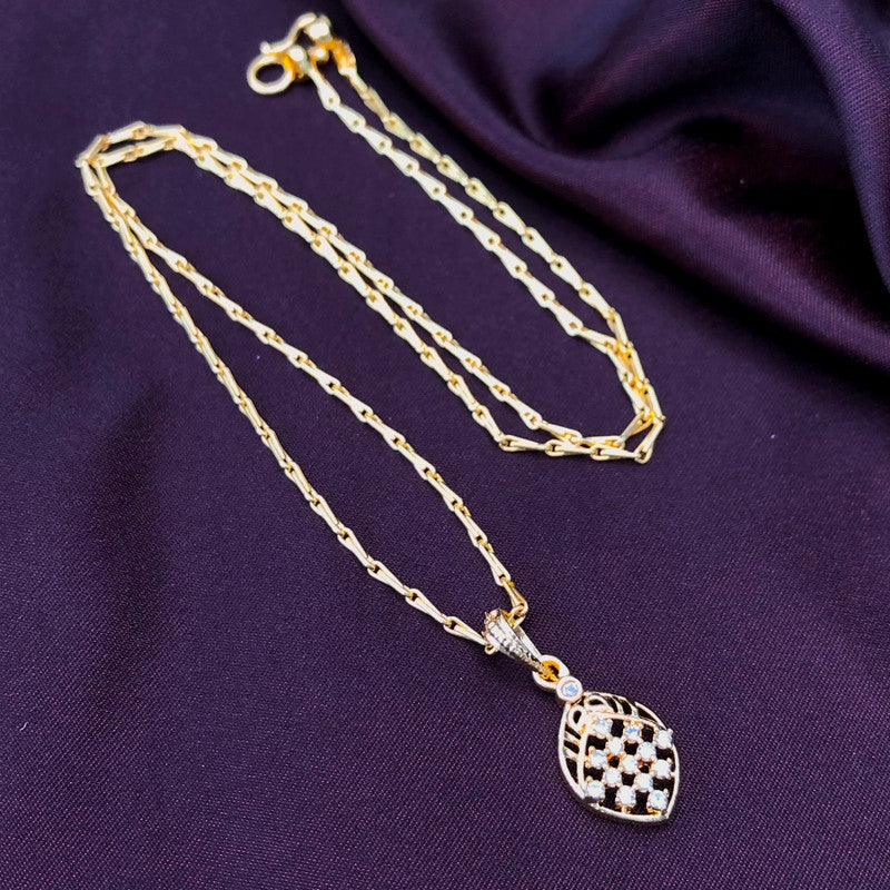 Gold chain necklace with a checkered pendant on a dark fabric background.