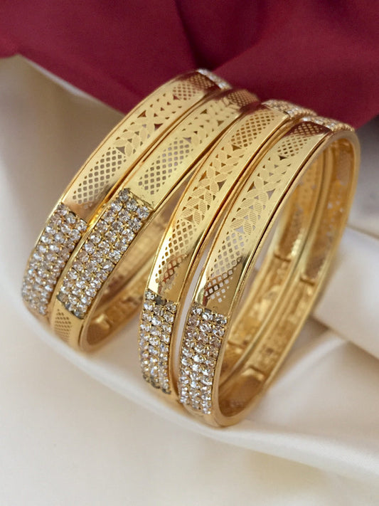 Three gold bangles adorned with intricate patterns and encrusted with small diamonds.