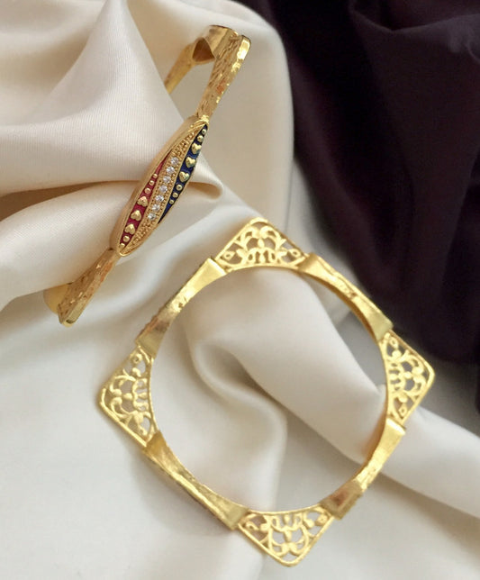 Two gold bangles with intricate designs, one featuring colorful gemstones.