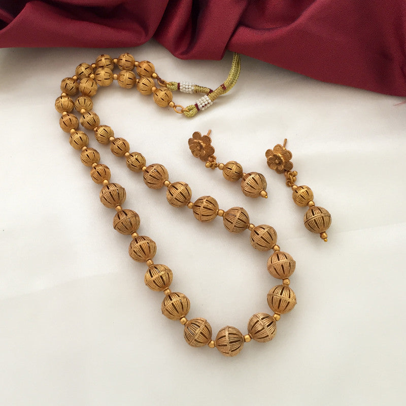 A set of golden beaded jewelry consisting of a necklace and matching earrings.