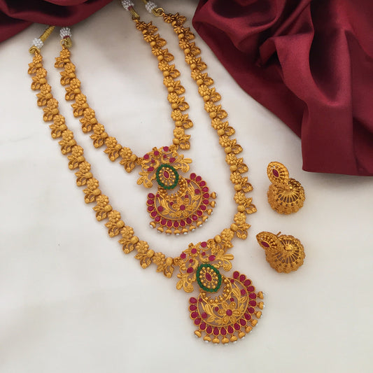 Two gold necklaces with intricate designs and red accents, accompanied by a pair of matching gold earrings.