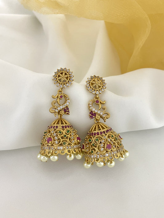 Gold jhumka earrings with intricate designs, adorned with pink and white stones, and pearl drops.