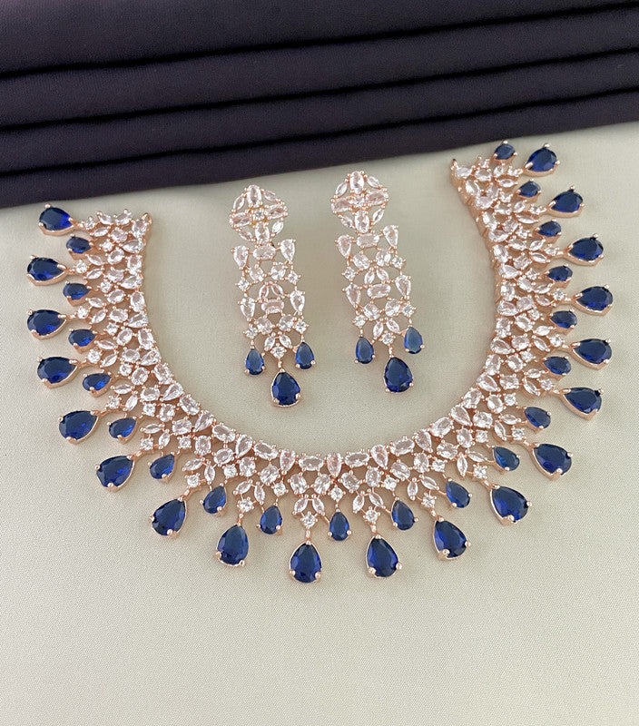 A set of jewelry featuring a necklace and matching earrings adorned with blue and clear gemstones.