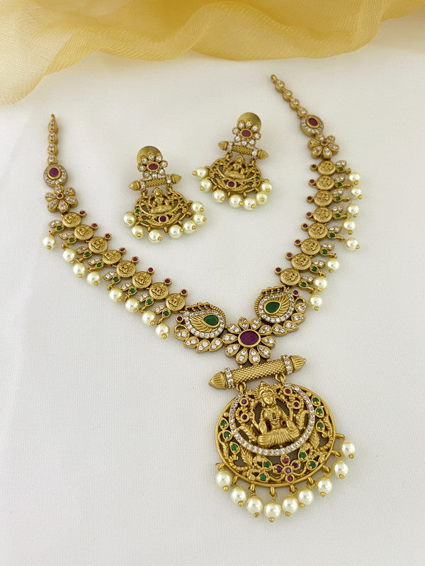 A gold necklace set with intricate designs, featuring green and red gemstones, pearls, and matching earrings.