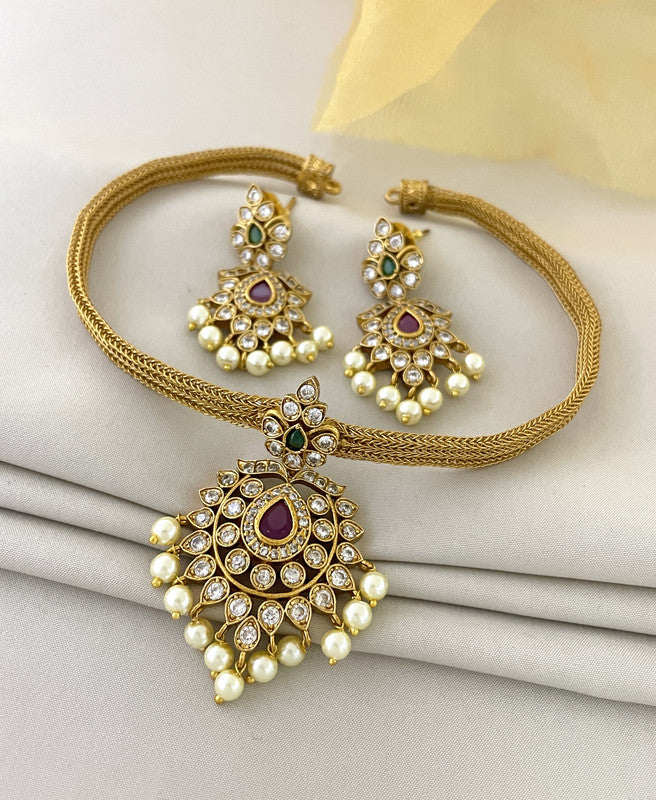 Gold necklace and earrings set with intricate design, featuring pearls and gemstones.