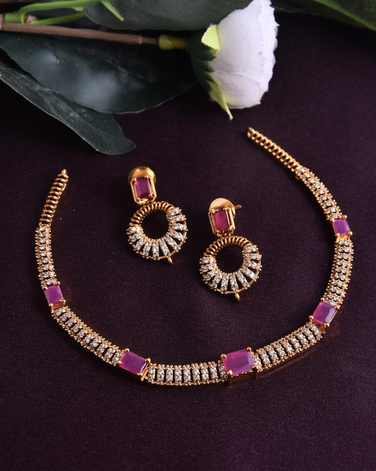 A gold necklace and earring set adorned with pink and white gemstones.