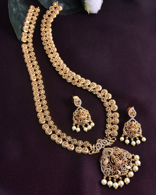 A gold necklace set with intricate designs, featuring a matching pair of earrings. The necklace and earrings are adorned with small pearls and detailed embellishments.