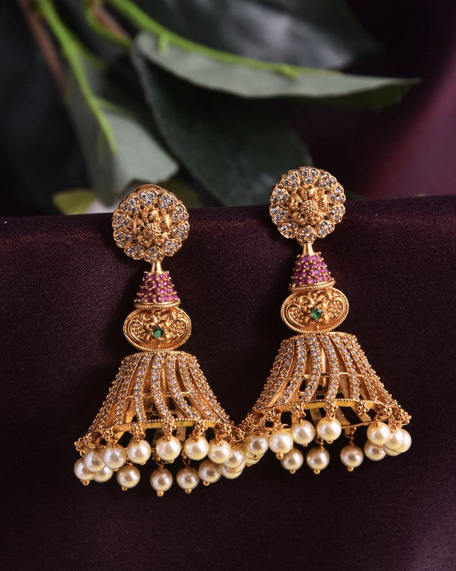 Gold jhumka earrings with intricate designs, adorned with pearls and gemstones.