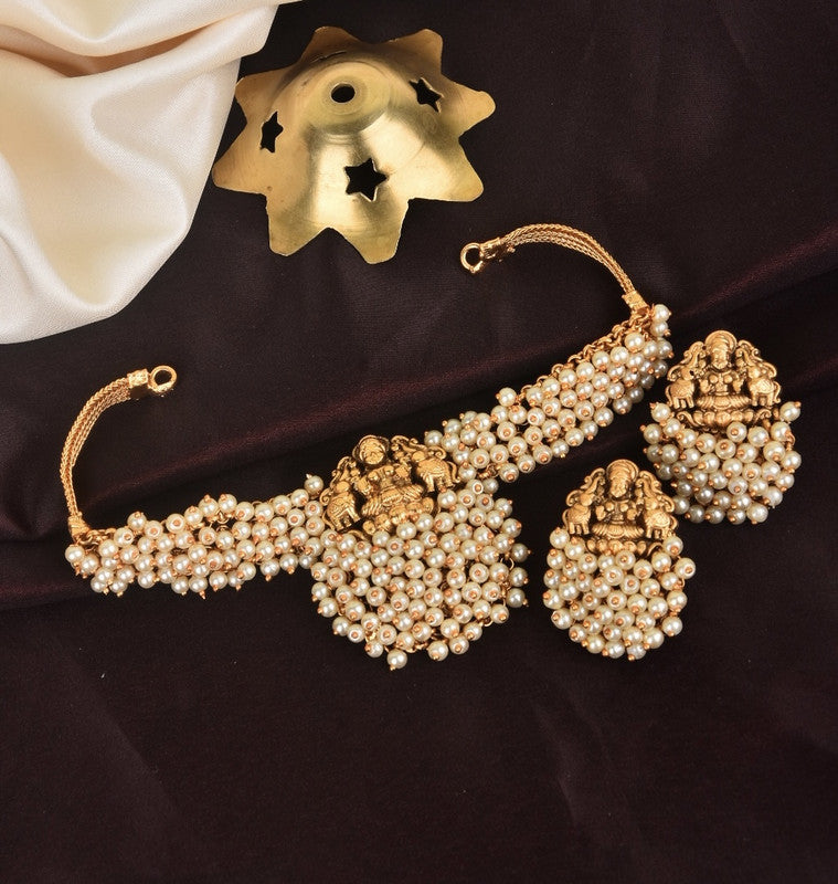 A gold-toned choker necklace and matching earrings adorned with clusters of white pearls and intricate deity designs.