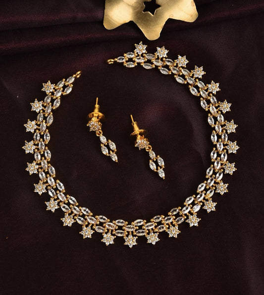 A gold and diamond necklace with matching earrings on a dark fabric background.