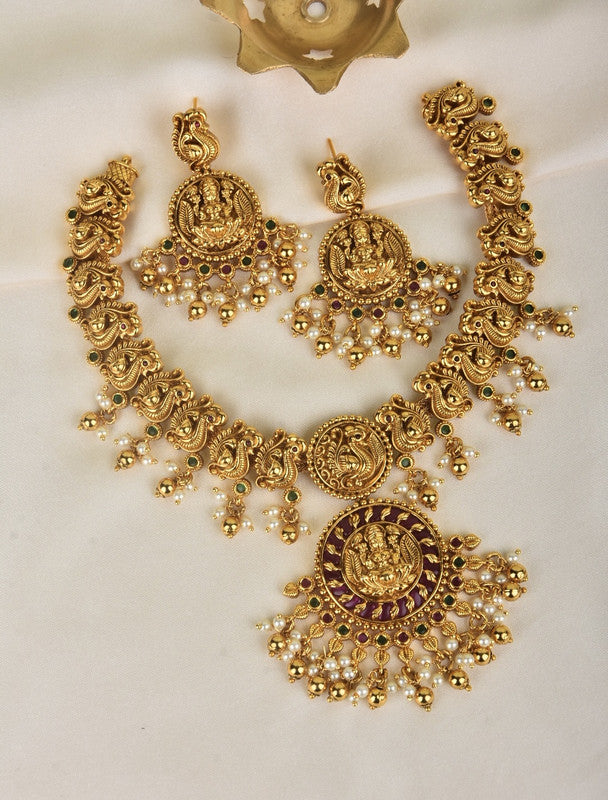 A set of traditional gold jewelry consisting of a necklace and matching earrings with intricate designs and dangling beads.