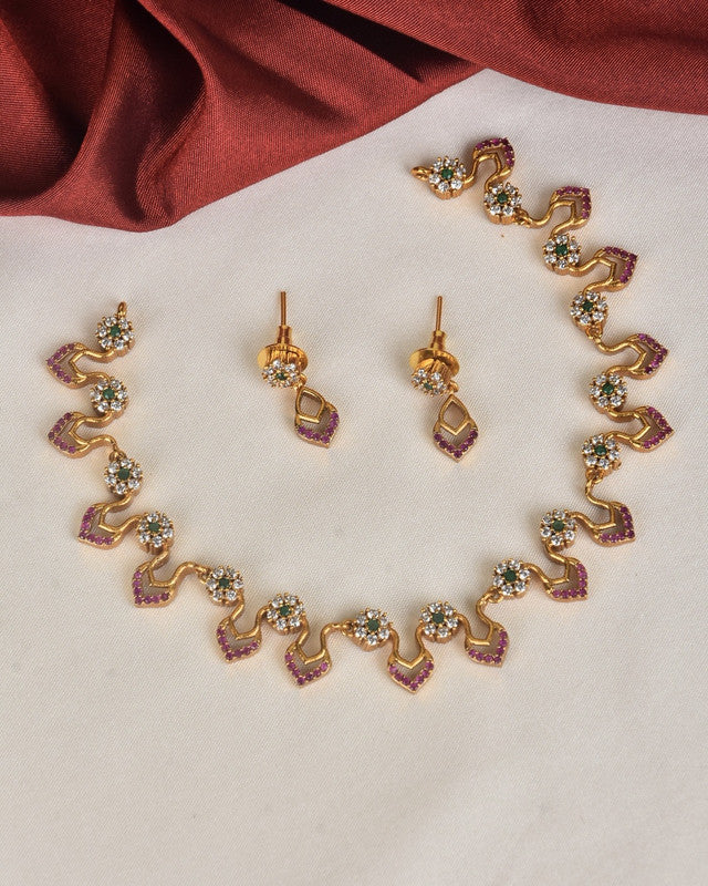 A gold necklace and matching earrings set with purple and white gemstones arranged in a wavy pattern.
