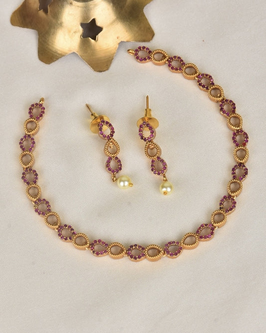 A gold bracelet and matching earrings with red gemstones and pearl drops.