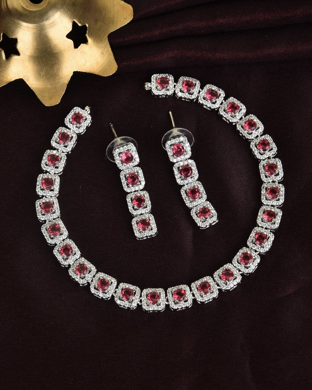 A jewelry set consisting of a bracelet and a pair of earrings, each featuring square-shaped red gemstones surrounded by clear stones.