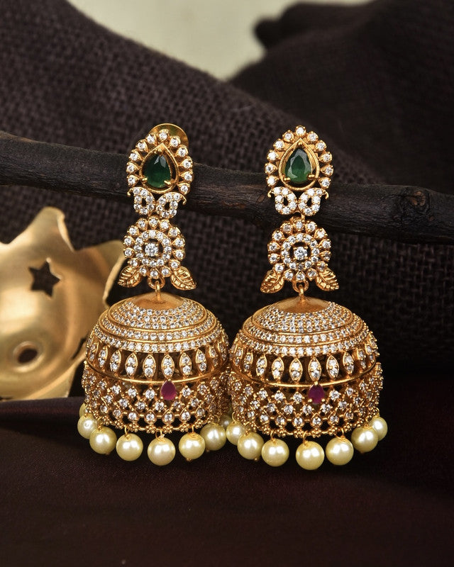 Gold jhumka earrings adorned with pearls and intricate gemstone detailing.