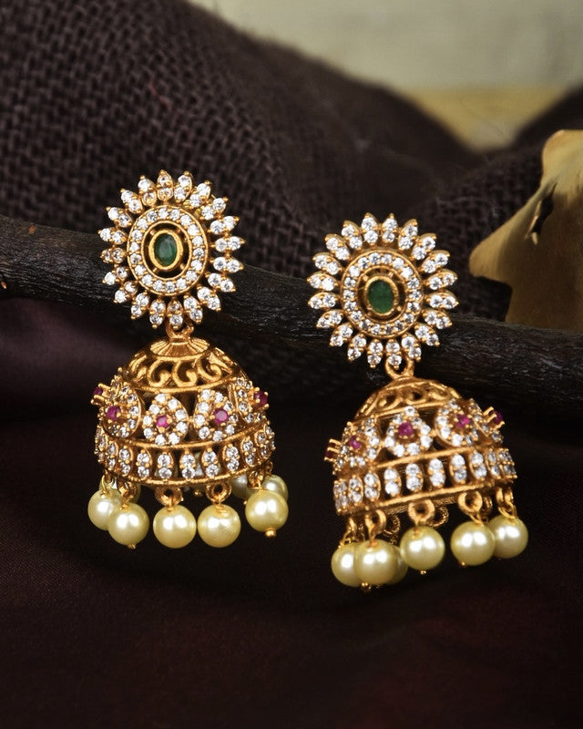 Gold jhumka earrings adorned with white and pink stones, featuring pearl drops.